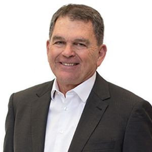 A photo of Jeff Holloway in a suit and smiling at the camera.